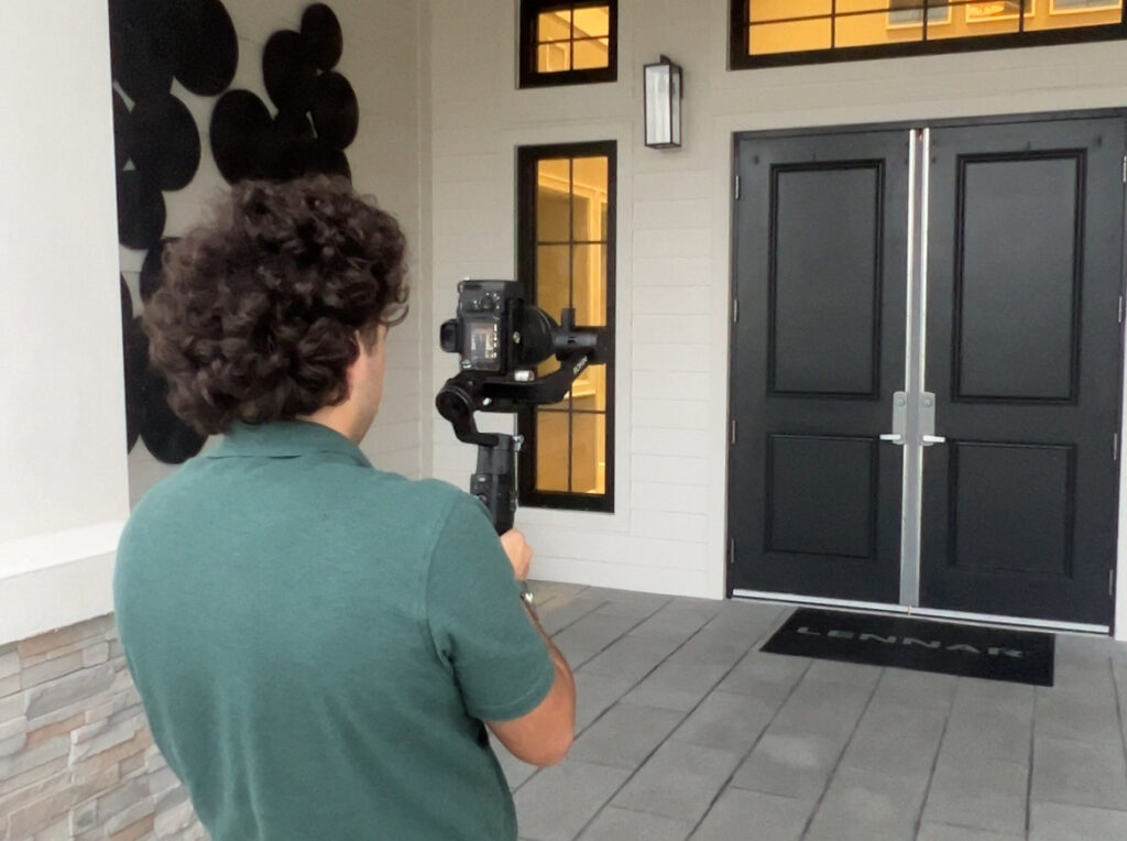 Tampa bay real estate videographer, Zeki Sert, holding a Camera wearing a green shirt